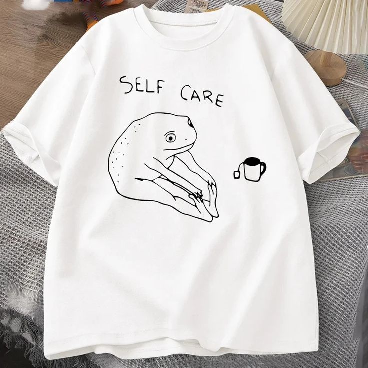 Cute white t-shirt with a simple frog drawing and “Self Care” caption, ideal for casual or aesthetic wear.