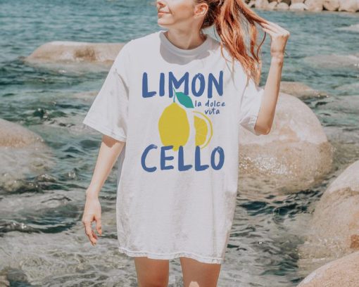White oversized t-shirt with a lemon graphic and text “Limoncello – la dolce vita” in blue and yellow
