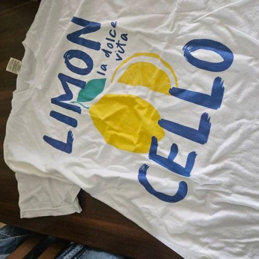 White oversized t-shirt with a lemon graphic and text “Limoncello – la dolce vita” in blue and yellow