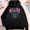 Black unisex hoodie with "Malibu Beach" pink and teal graphic print, kangaroo pocket, and drawstring hood