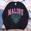 Streetwear-style black crewneck sweatshirt with bold Malibu Beach lettering in pink and teal.