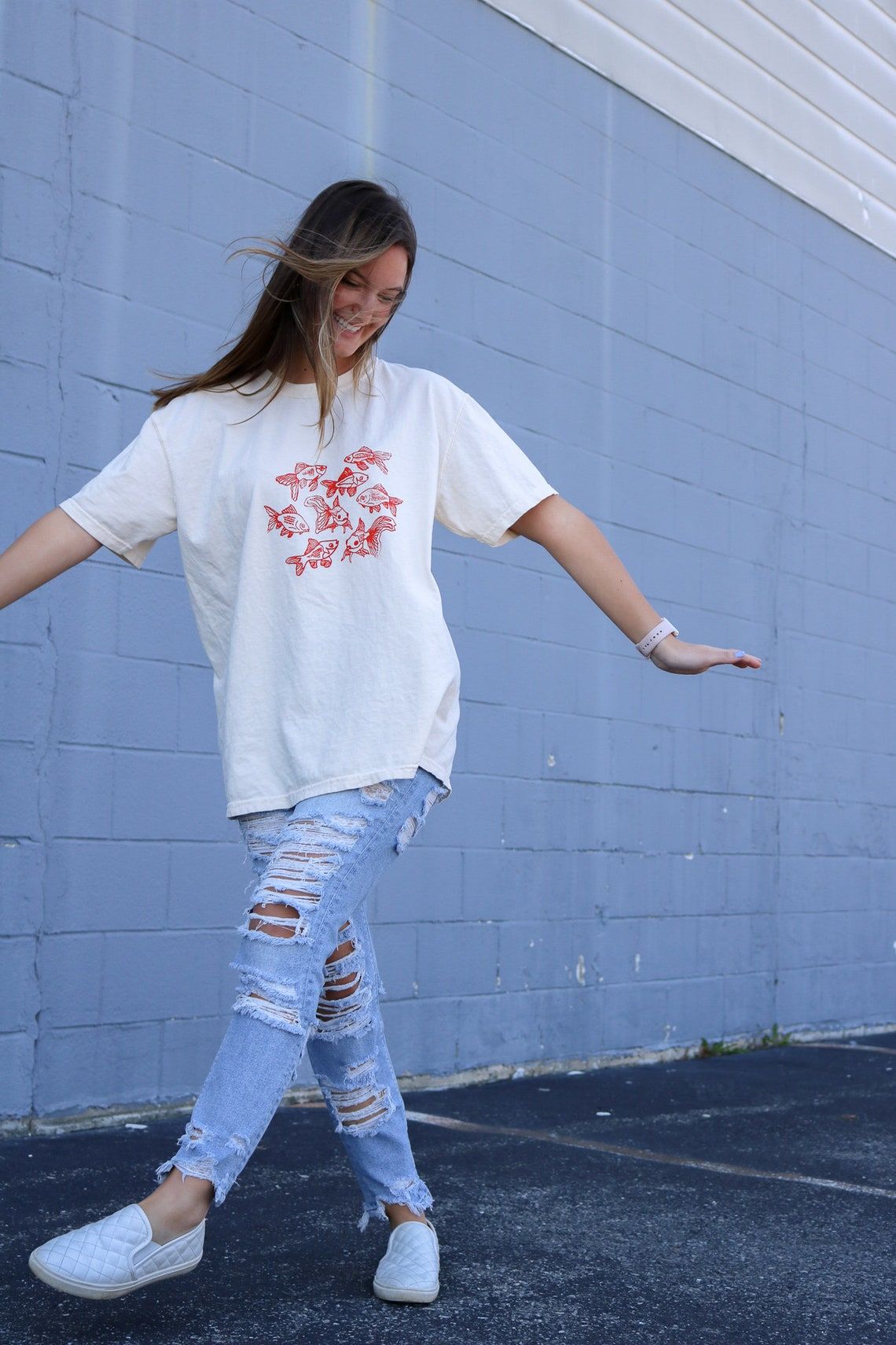 Beige t-shirt featuring a group of hand-drawn red goldfish in a minimalist, sketch-style design