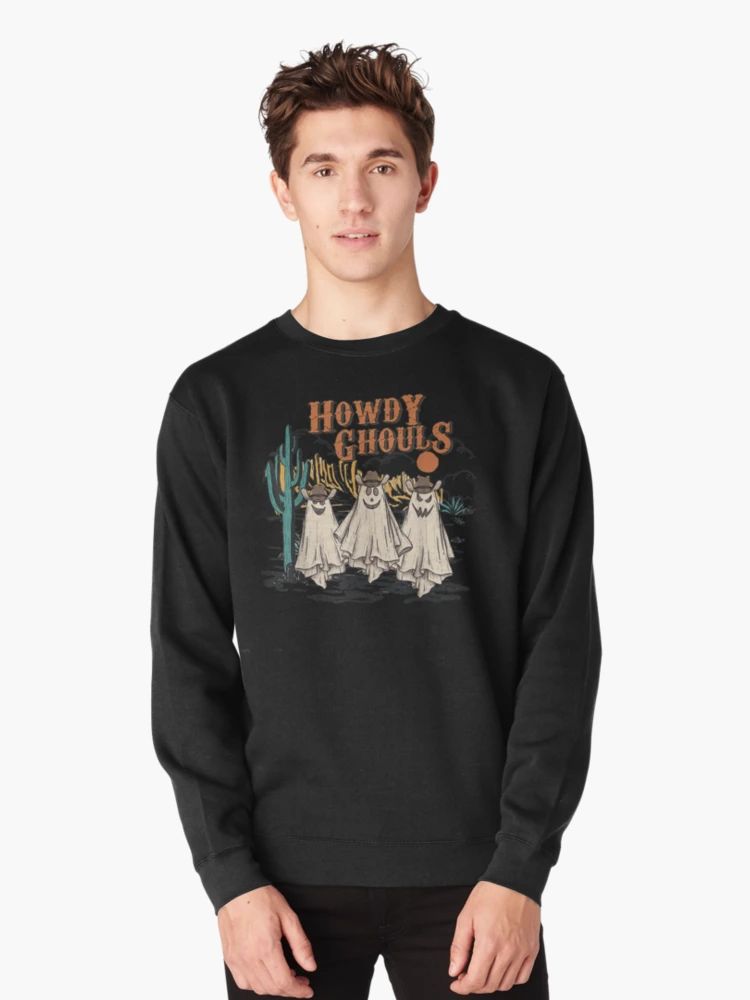 Howdy Ghouls Spooky Season Cowgirl Halloween Sweatshirt Black Sweatshirt featuring three cartoon ghost cowgirls in a desert scene with “Howdy Ghouls” text, worn by male model