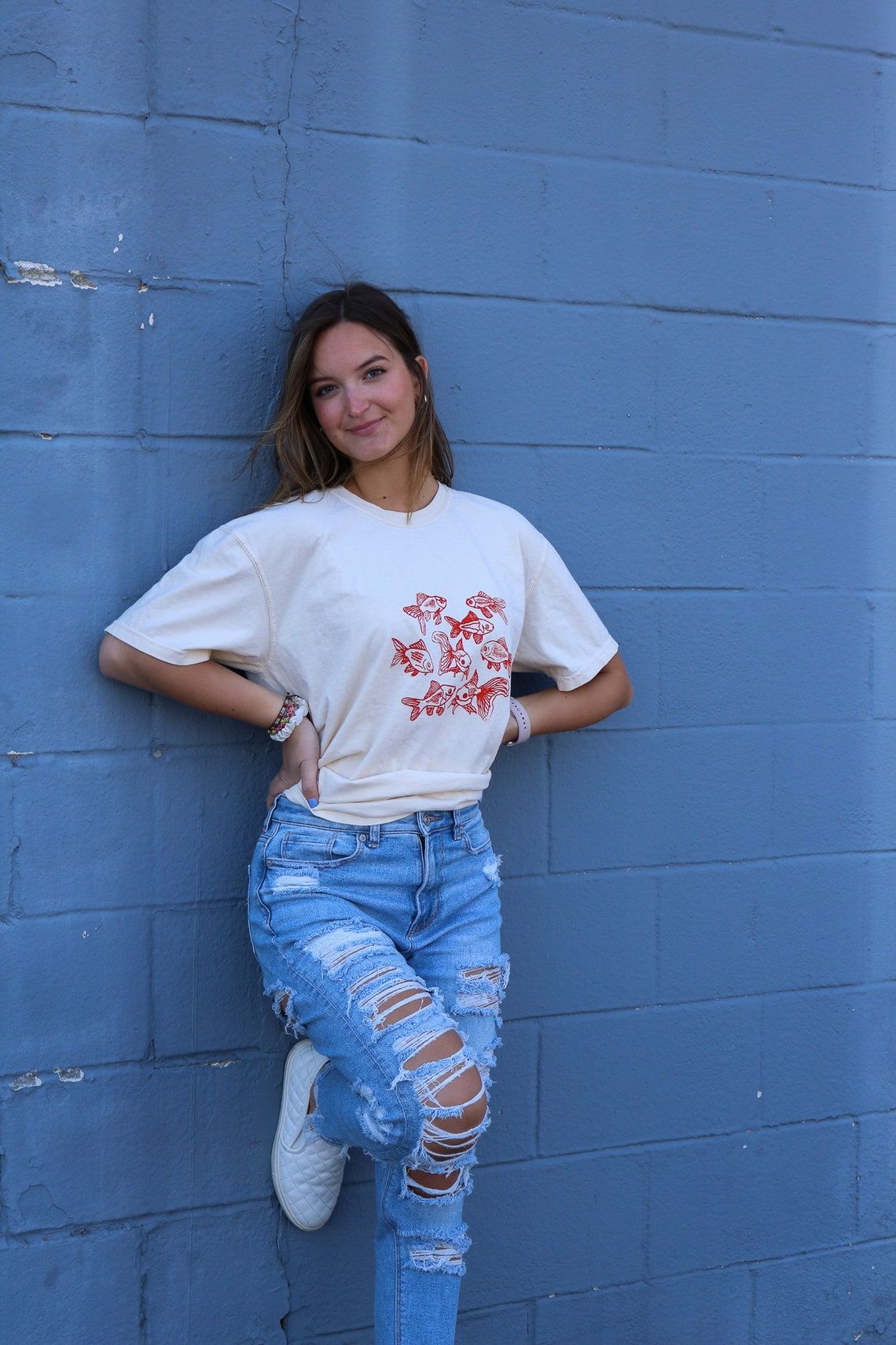 Beige t-shirt featuring a group of hand-drawn red goldfish in a minimalist, sketch-style design