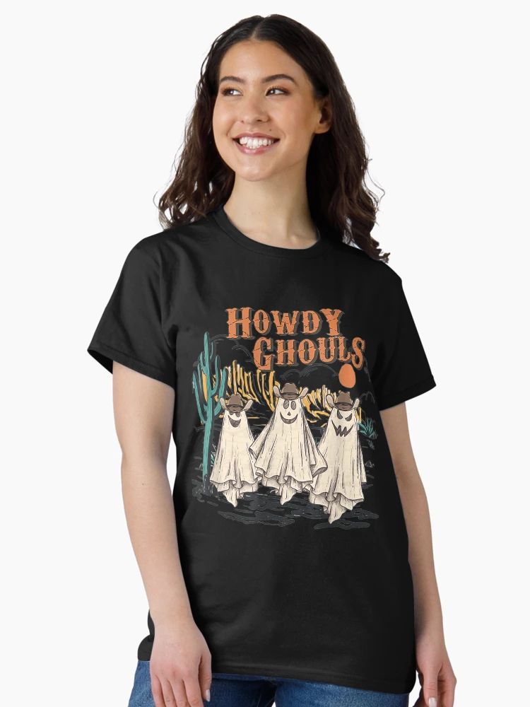 Howdy Ghouls Spooky Season Cowgirl Halloween T-Shirt Women Black t-shirt featuring three cartoon ghost cowgirls in a desert scene with “Howdy Ghouls” text, worn by male model
