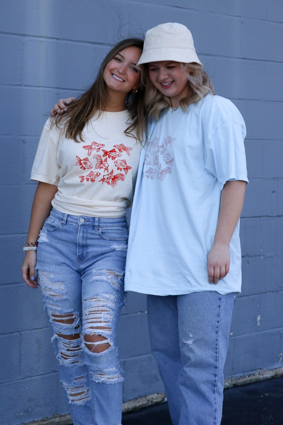 Beige t-shirt featuring a group of hand-drawn red goldfish in a minimalist, sketch-style design