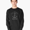 Black sweatshirt featuring “Collinsport 1972 Maine” text and a grey anchor graphic, modeled by a young man.