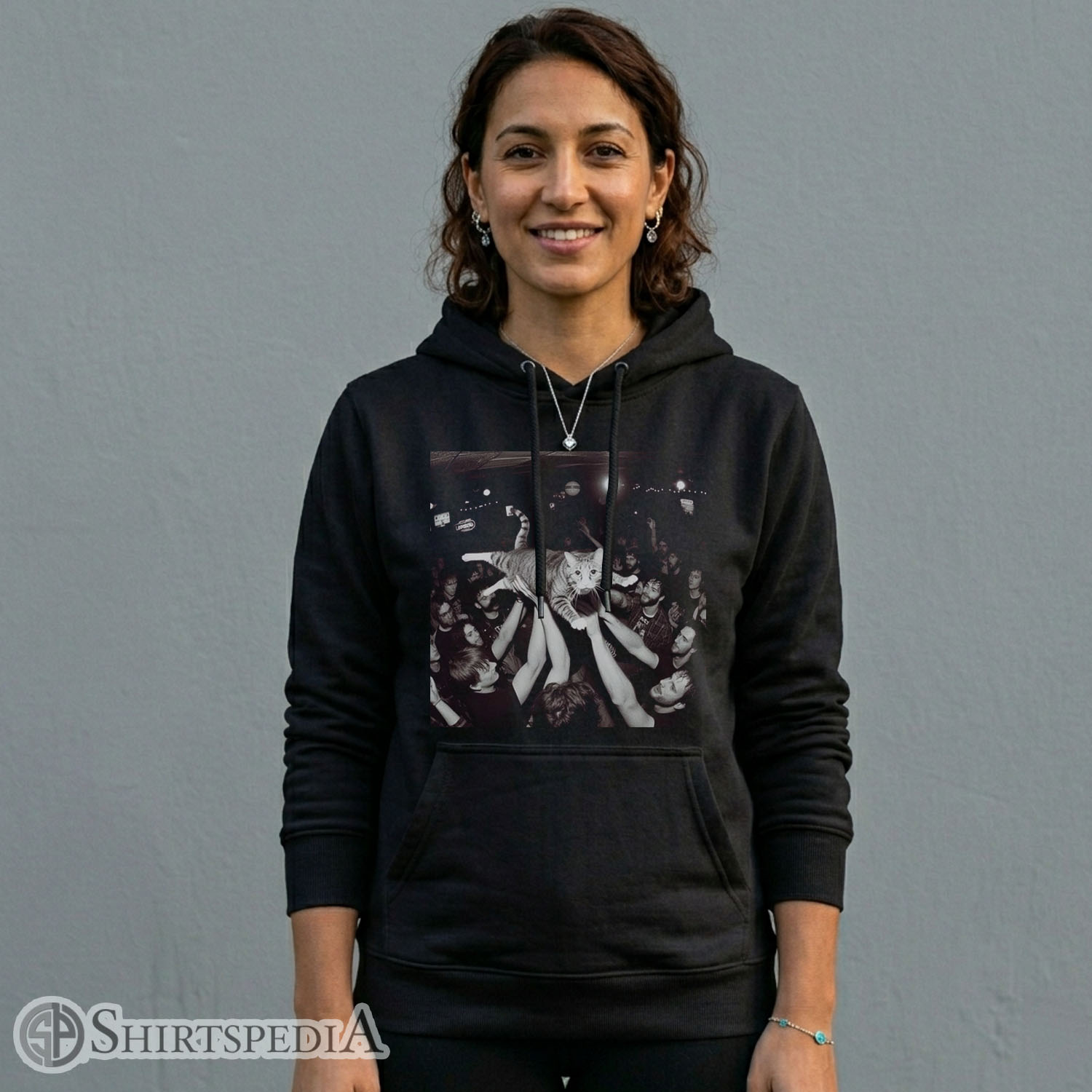 Womens Heavyweight black streetwear hoodie with an adjustable drawstring hood, displaying a large central graphic of a cat crowd surfing at a rock concert.