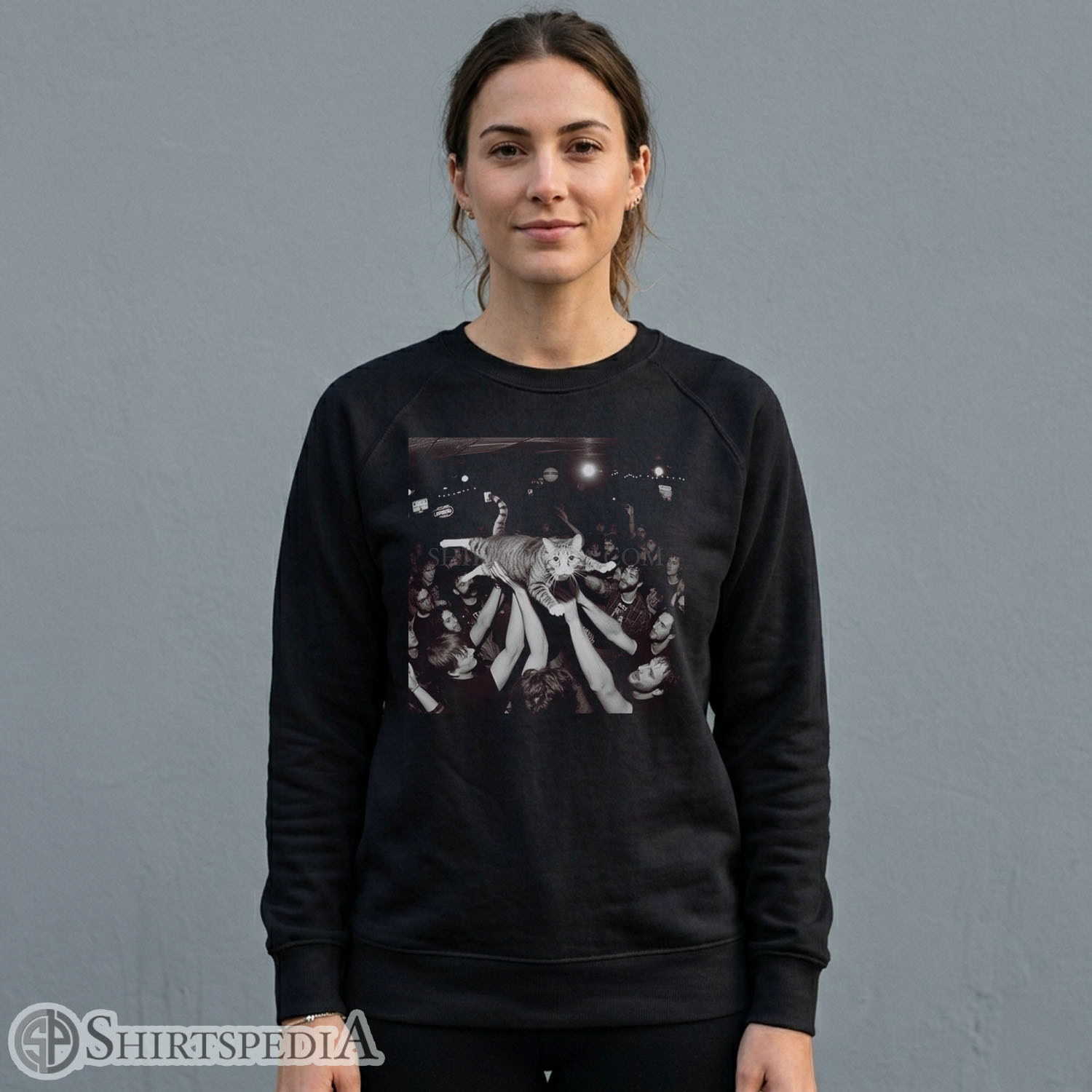 Women black crewneck pullover sweatshirt featuring a large central graphic of a crowd-surfing cat at a live rock concert.
